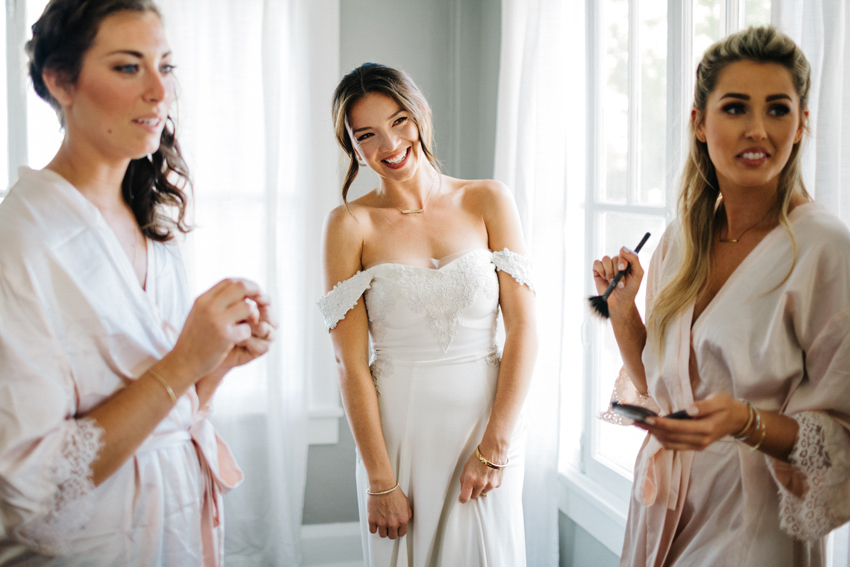 bride laughing with her bridesmaids the morning of the wedding