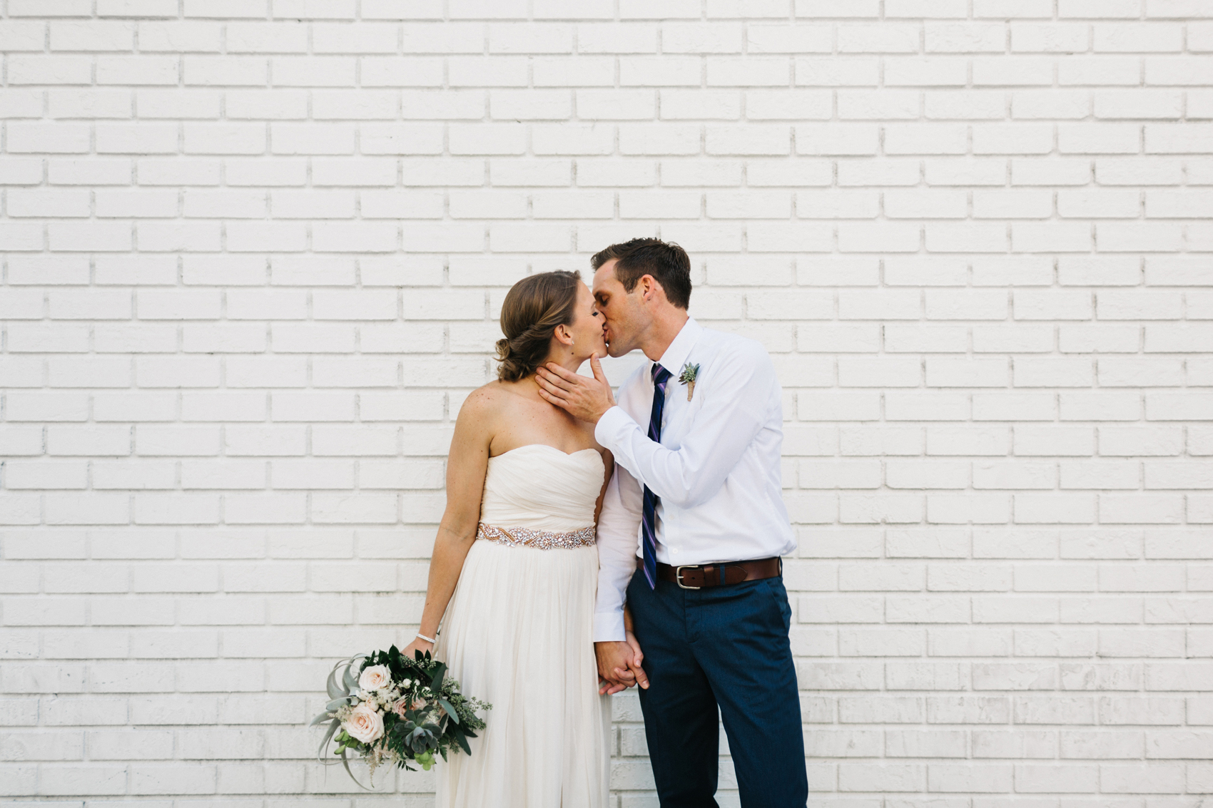 St. Pete Wedding Photographer with natural light, candid wedding photos against a brewery white brick wall