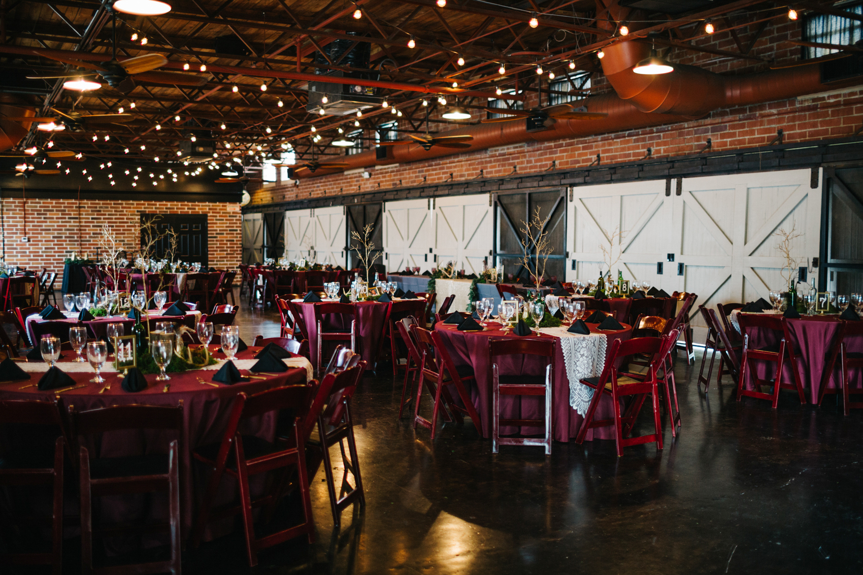 Burgundy boho wedding reception at the Winter Park Farmers Market with exposed brick walls and string lights