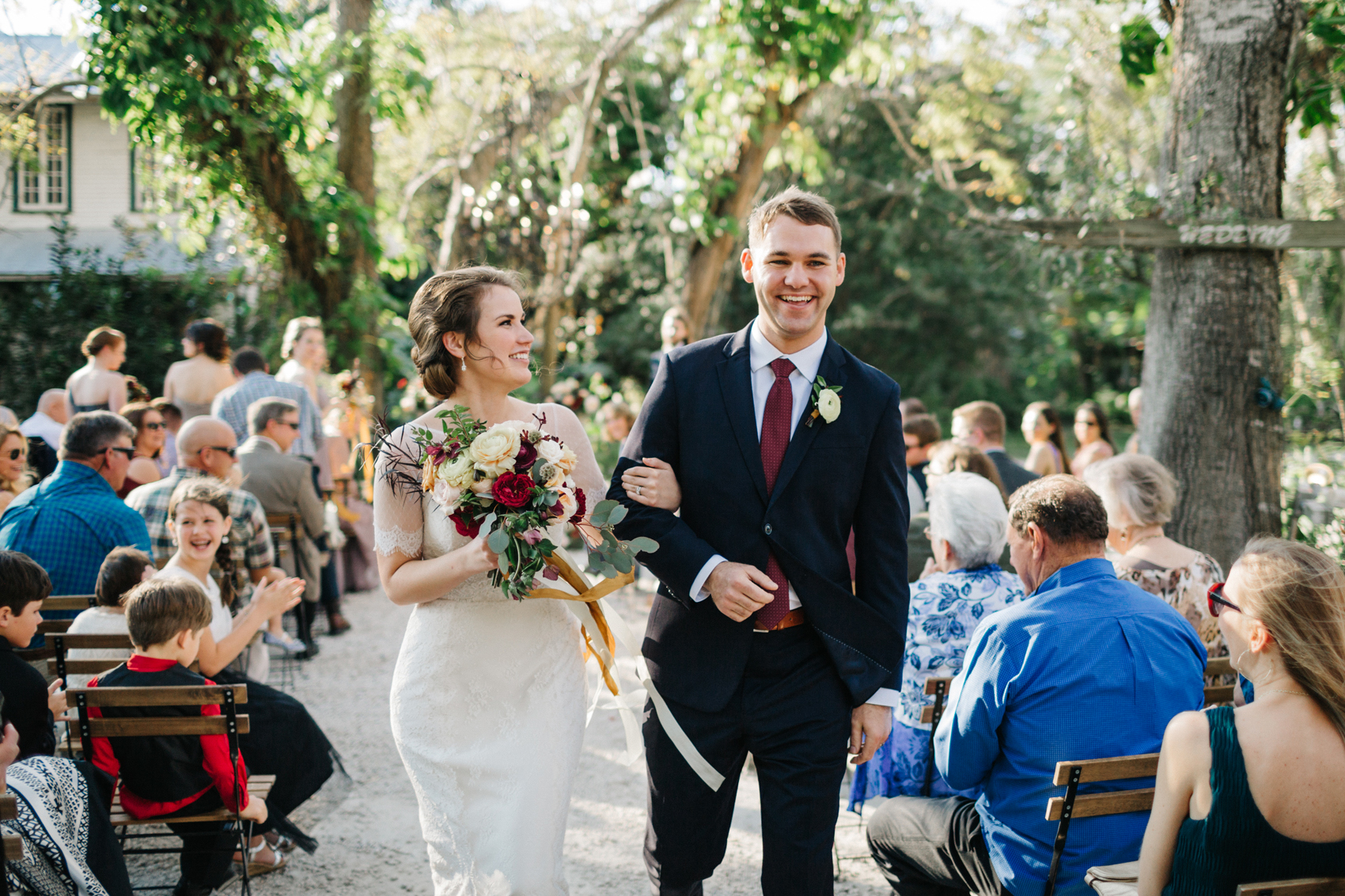bride and groom laughing and smiling as they walk down the aisle after exchanging vows at their Orlando garden wedding outdoor ceremony