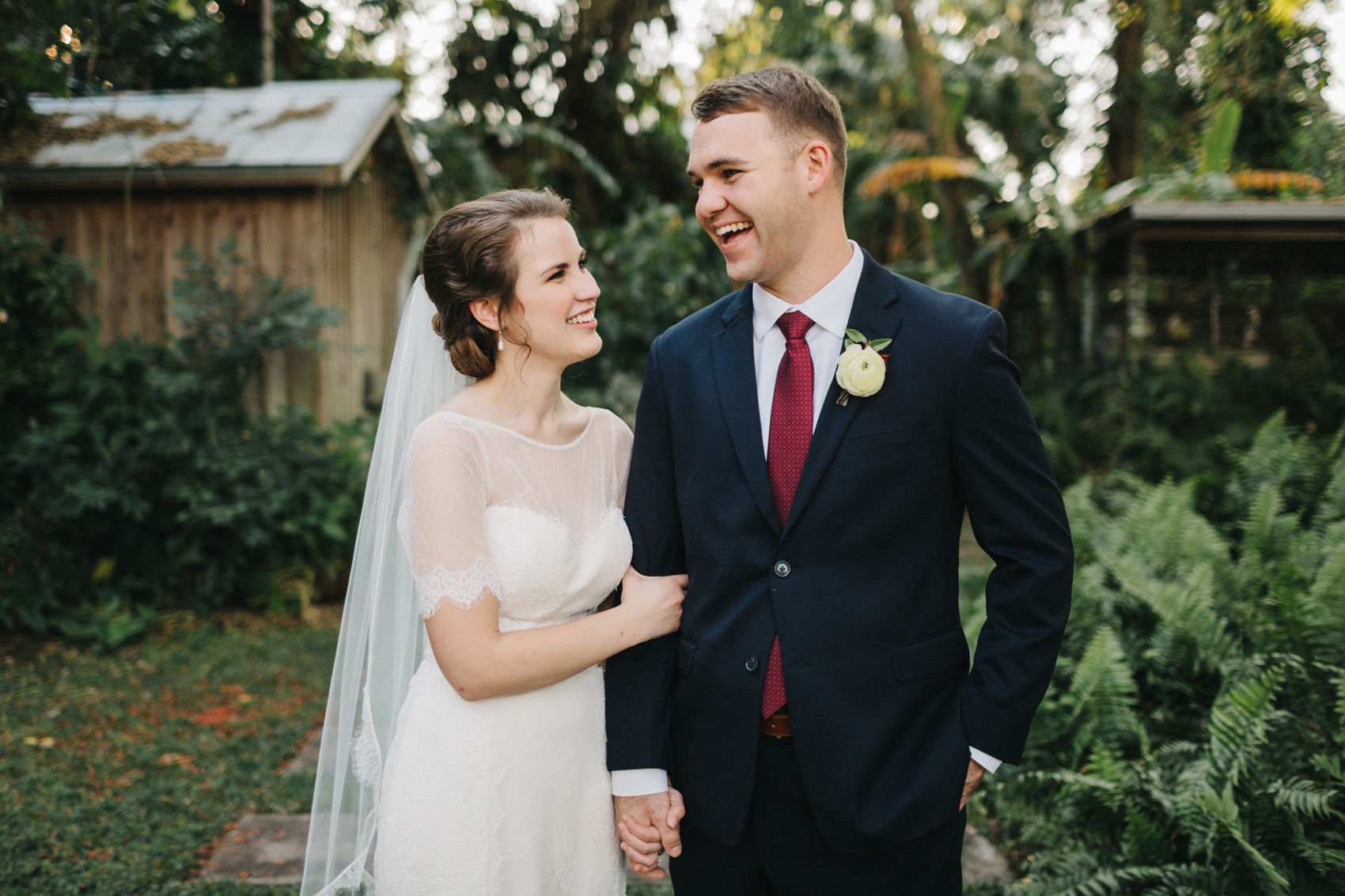 groom wearing a burgundy tie and laughing with his bride in the garden at their outdoor ceremony in the garden near Orlando, Florida by Florida wedding photographer