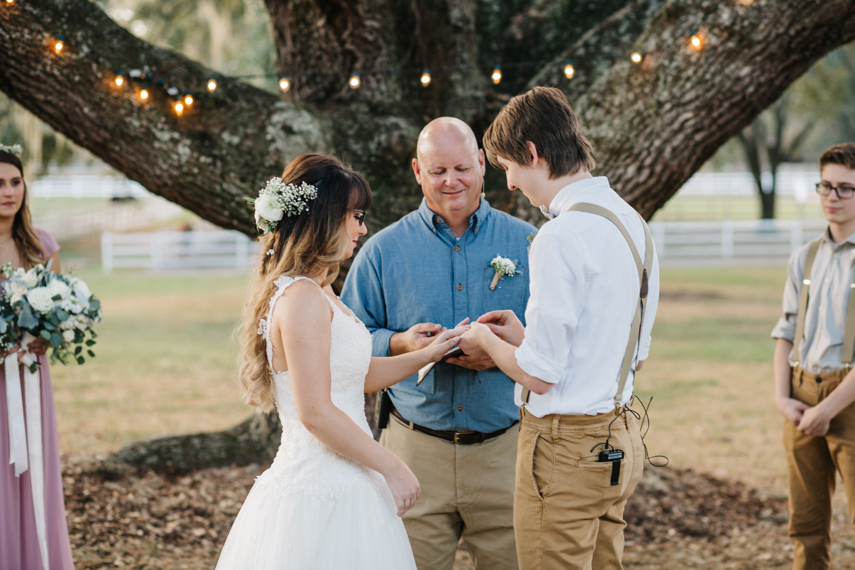 groom slipping on the wedding band during the outdoor ceremony under the oak trees in tampa, florida