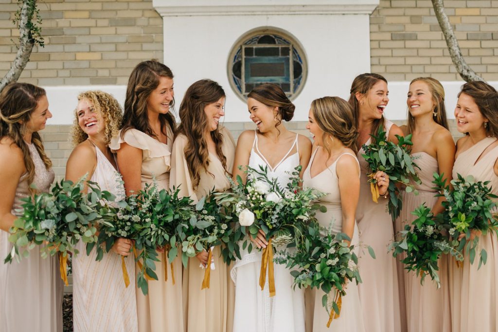 bridesmaids wearing nude dresses and lush organic bouquets of greenery and silk ribbon