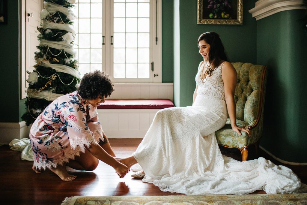 maid of honor helping the bride put her flats on
