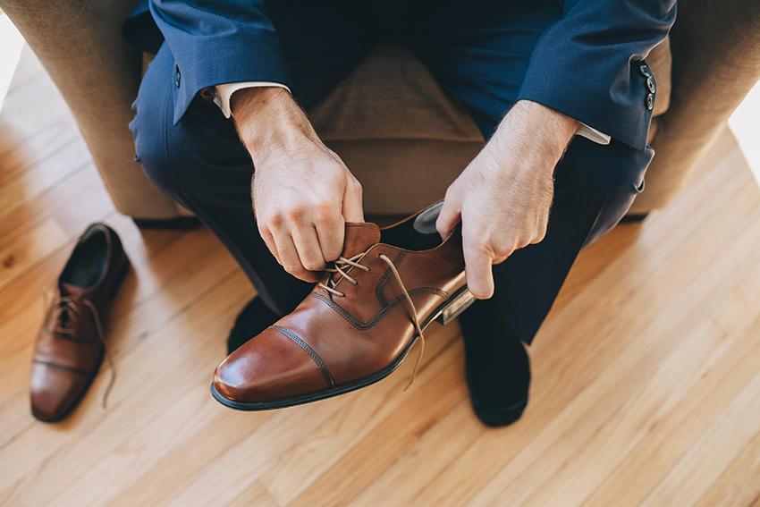 Groom putting brown shoes on