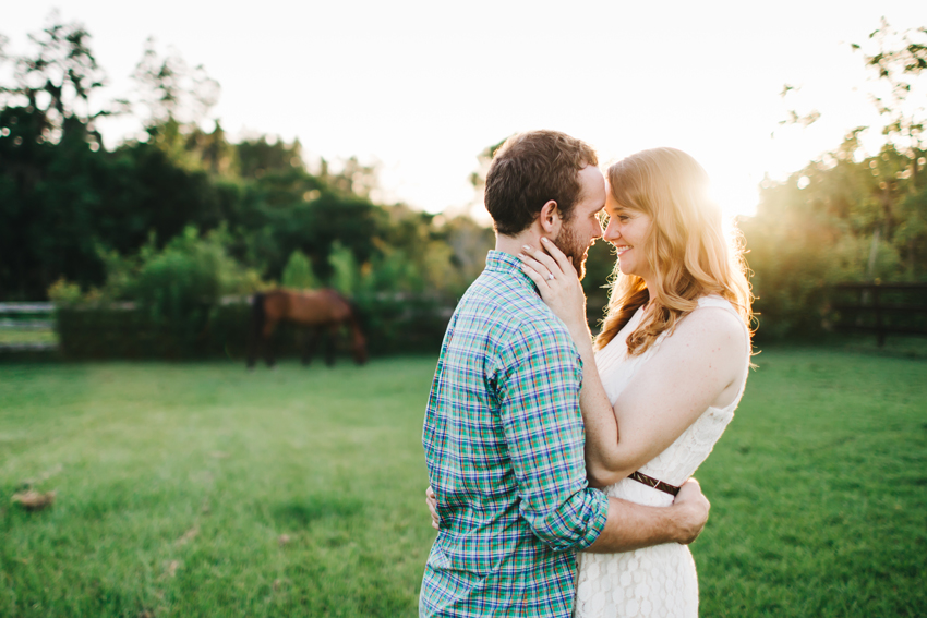 Natural and candid engagement session photos at a horse barn at sunset