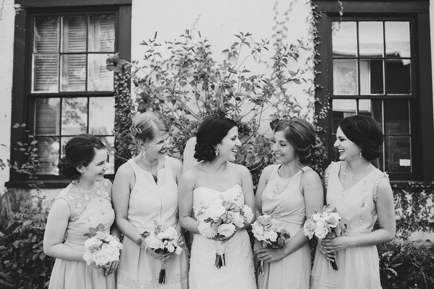 Bridesmaids laughing in front of a romantic ivy and flower wall