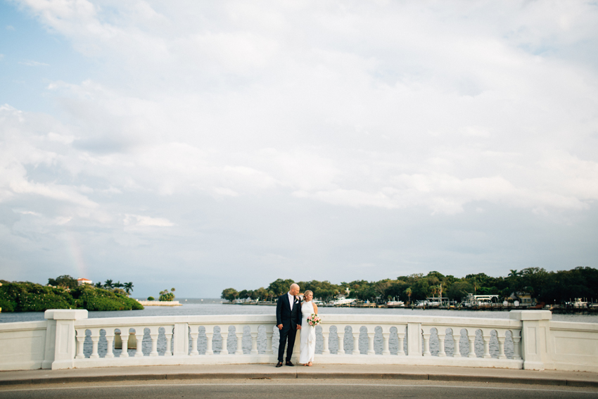 Romantic bride and groom standing on the bridge at sunset after their waterfront ceremony in St. Pete Florida