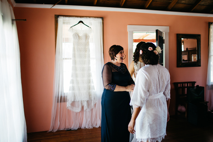 happy moment between mom and bride before putting on her beaded wedding dress