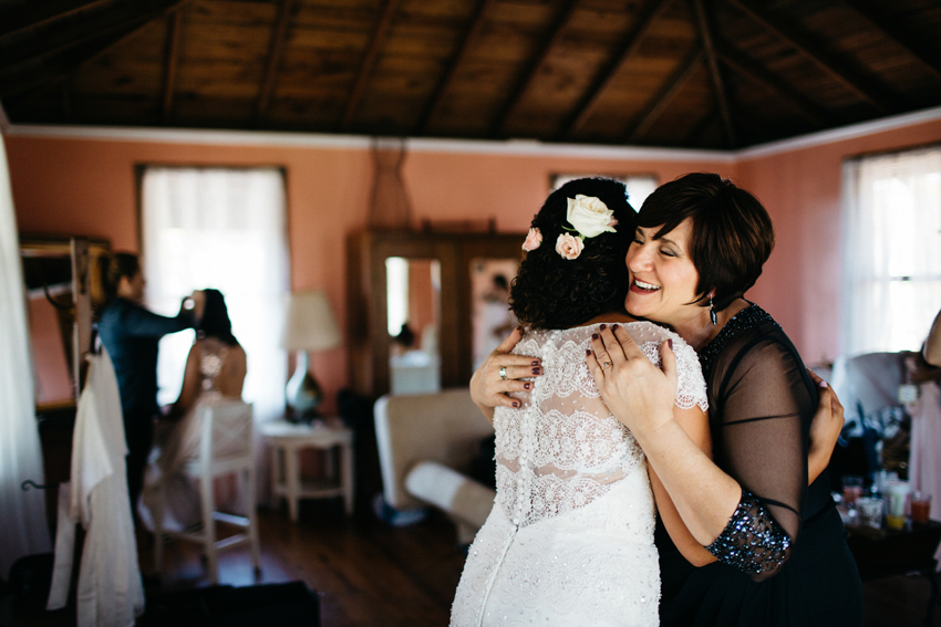 sweet moment with of the mother of the bride hugging her daughter in her beaded wedding dress