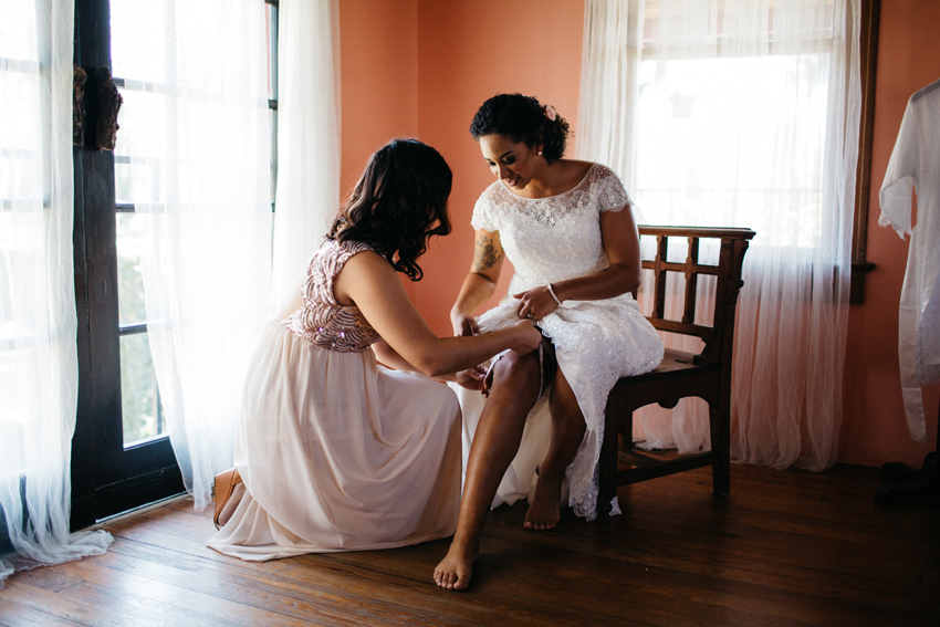 maid of honor helping the bride put on her vintage lace garter before her ceremony