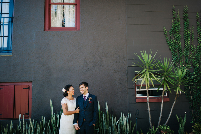 Bride and groom laughing in front of ivy covered wall at their creative outdoor wedding at The Acre in Orlando, Florida