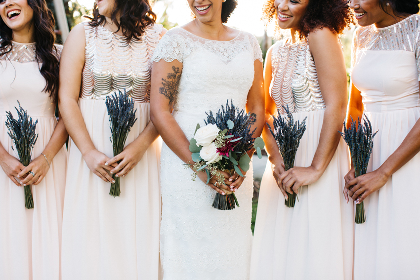 Stylish bridesmaids wearing blush sequin dresses and holding their dried lavendar bouquets