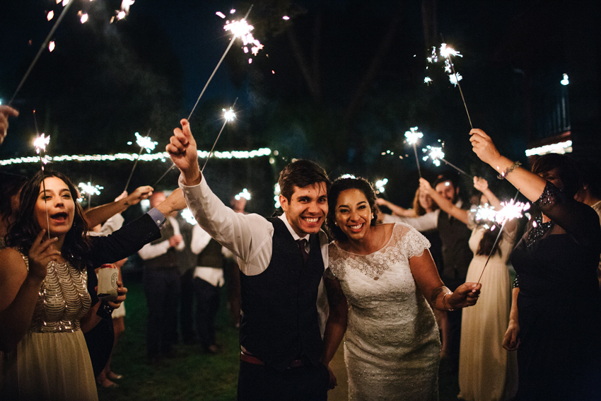Bride and groom laughing as they leave the wedding with sparklers