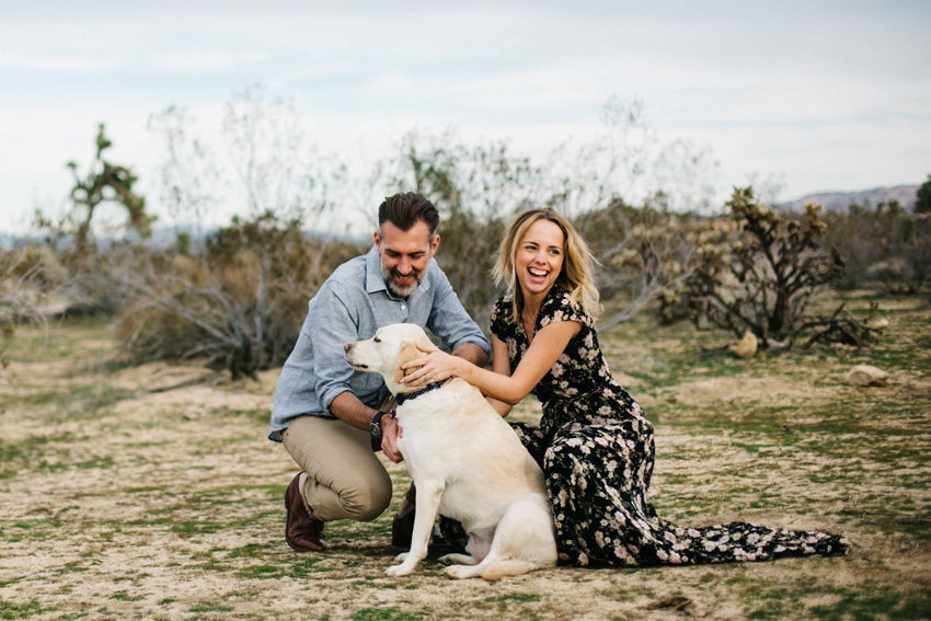 Couple snuggling with their dog in the desert at Joshua Tree park