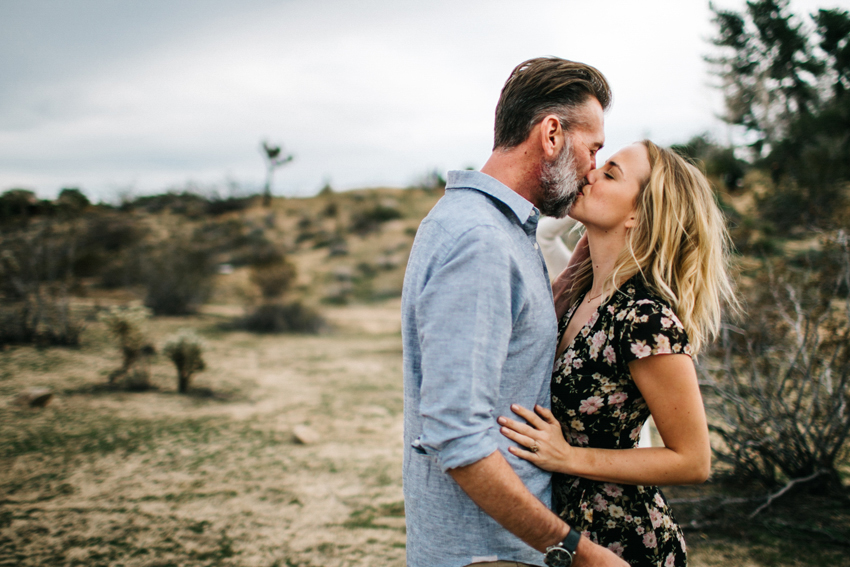 Couple kissing in the desert surrounded by Joshua Trees