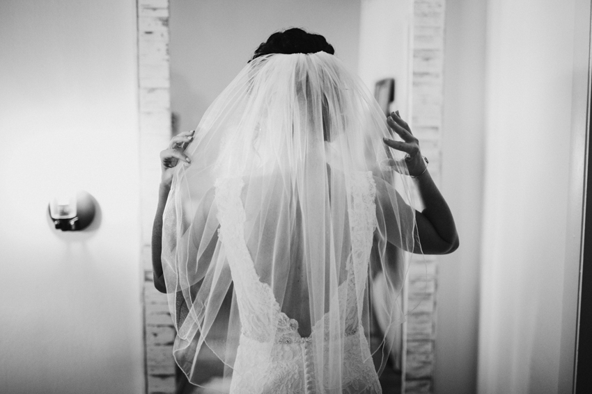 Bride fixing her romantic veil in the mirror of the bridal suite