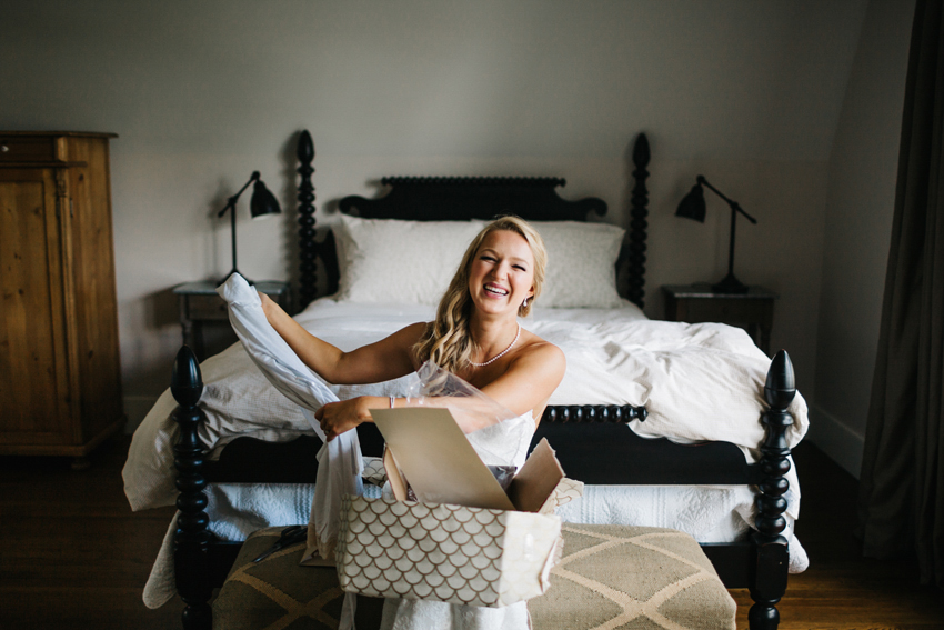 Bride laughing as she opens the presents from her thoughtful groom