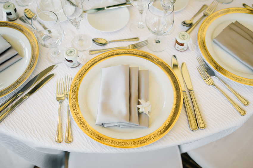 Gold and white placesettings with grey napkins and gold flatware