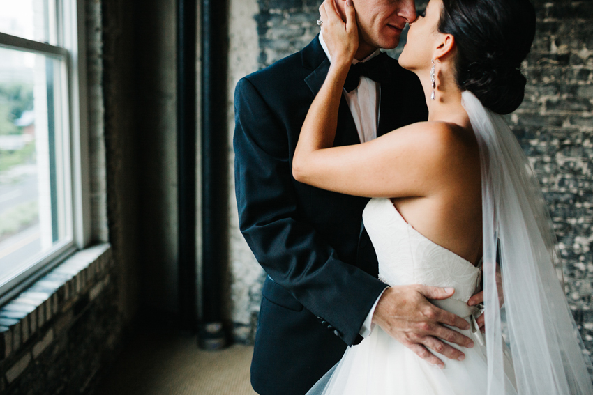 Romantic candid wedding photos with window light in an exposed brick wall room