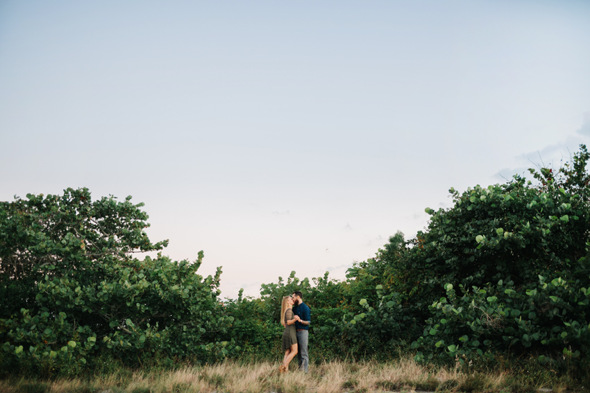 Anniversary photos in a field featuring chambray shirt oufit with tattoos and a olive green lace dress for engagement session outfits