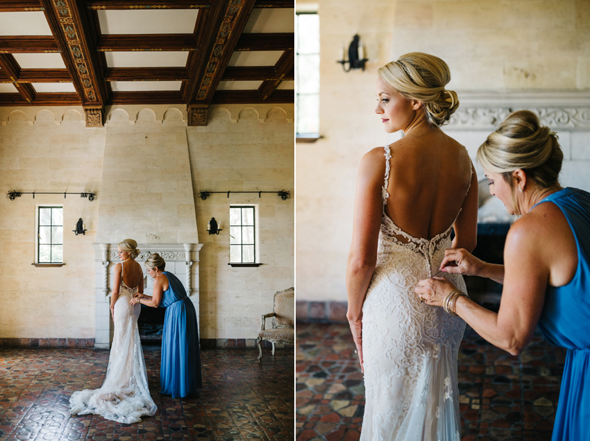 Bride putting on her dress in front of the histroic fireplace at the Powel Crosley Estate in Sarasota