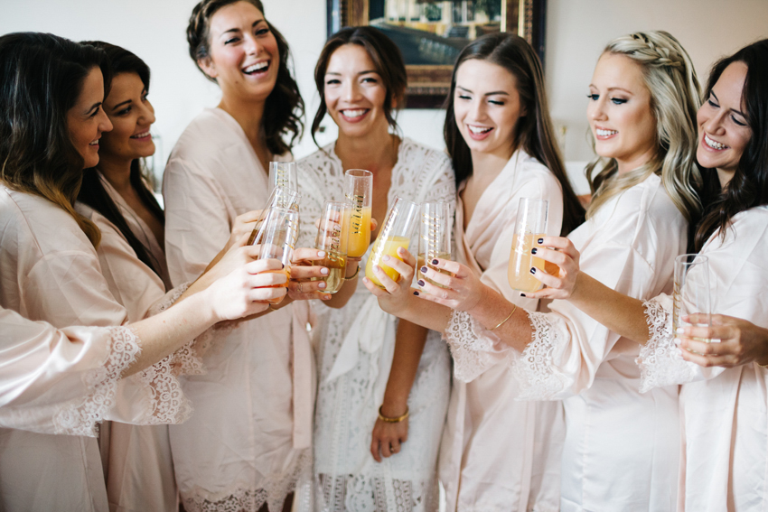 bride laughing with her bridesmaid sipping mimosas