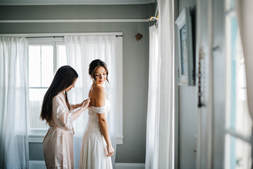 bride putting on her customized reformation dress on the wedding day