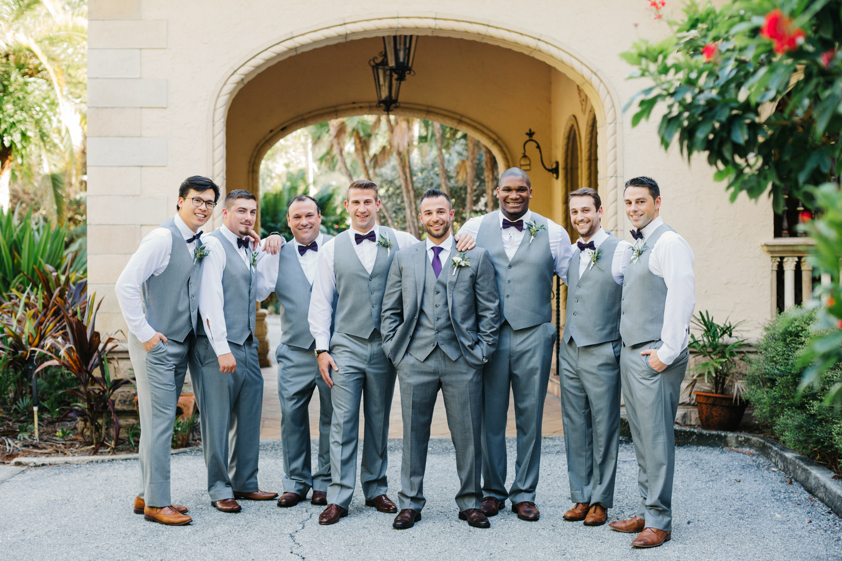 Groom hanging out with his groomsmen before the ceremony wearing grey suits and vests