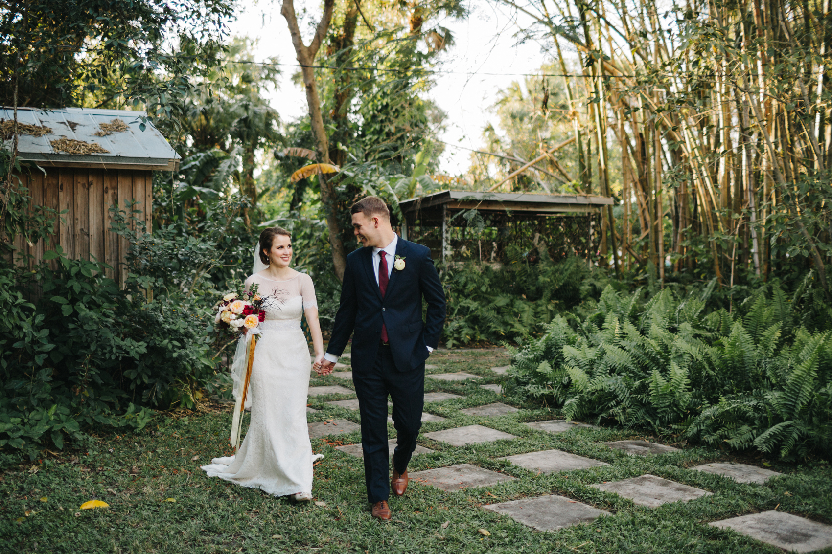 Candid wedding portrait of the bride and groom walking in the garden after their Florida outdoor ceremony