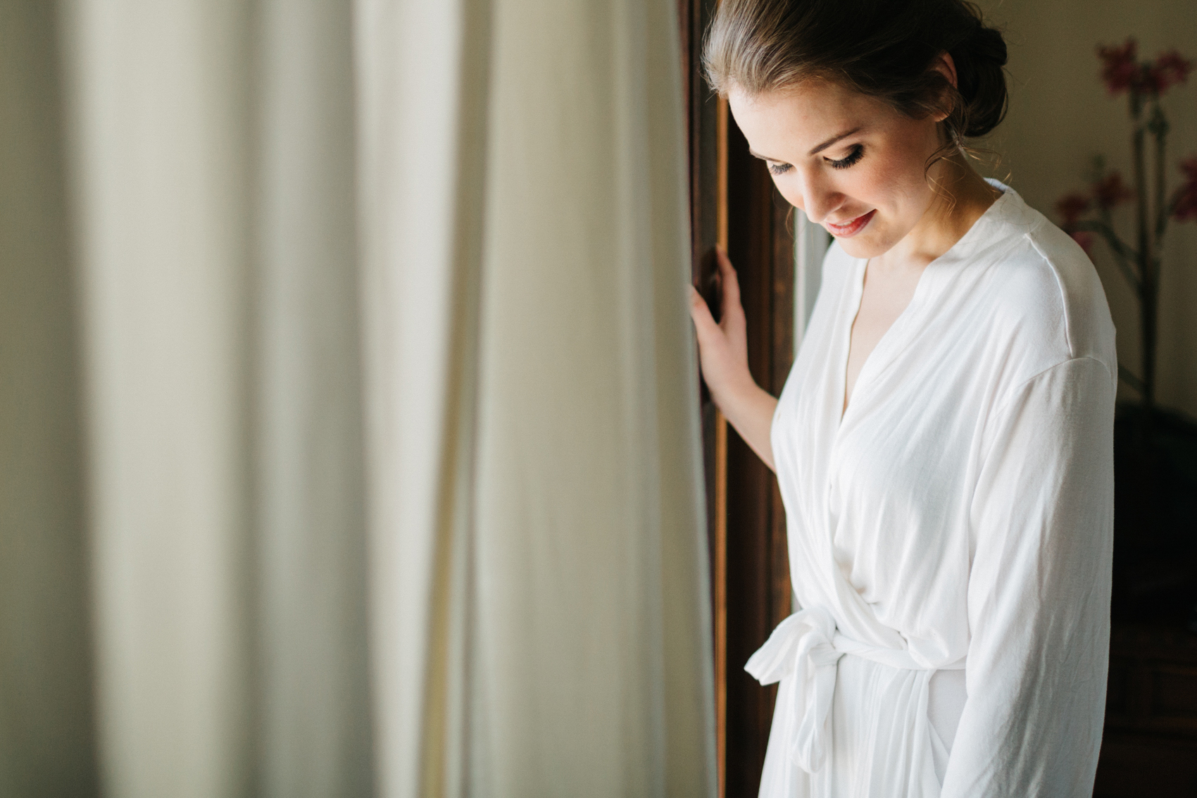 bridesmaid wearing a white lace bridal robe while she gets ready to put her Amy Kuschel ‘London’ dress on