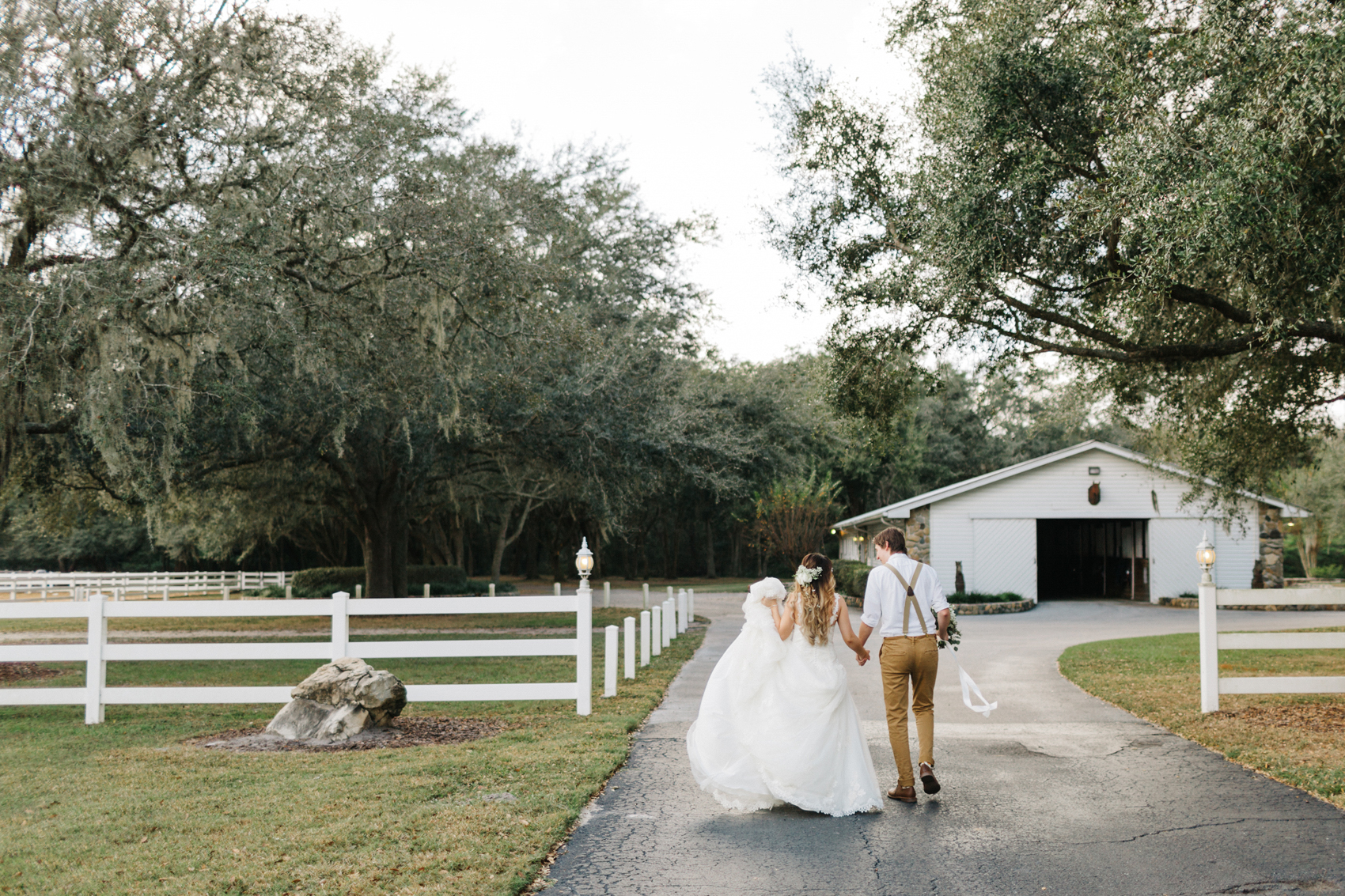 bride and groom walking through the rustic farm by the white barn in Florida before their wedding