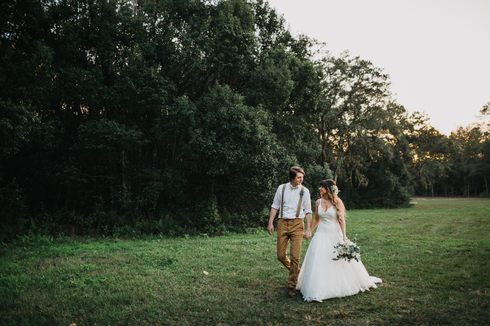 bride and groom walking along the rustic farm before their barn reception under the twinkle lights in tampa, florida