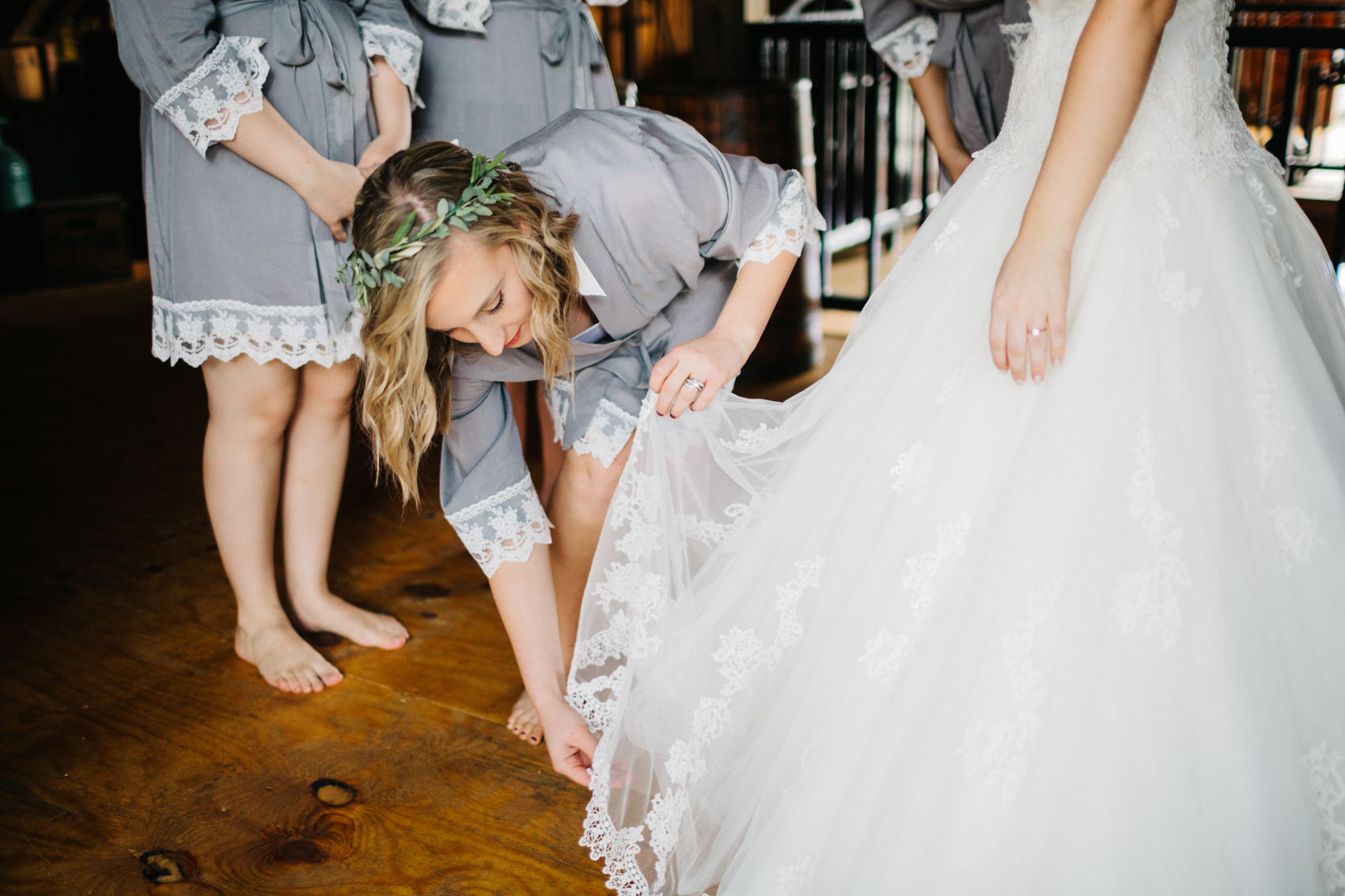 bridesmaid wearing a grey robe and helping the bride get ready