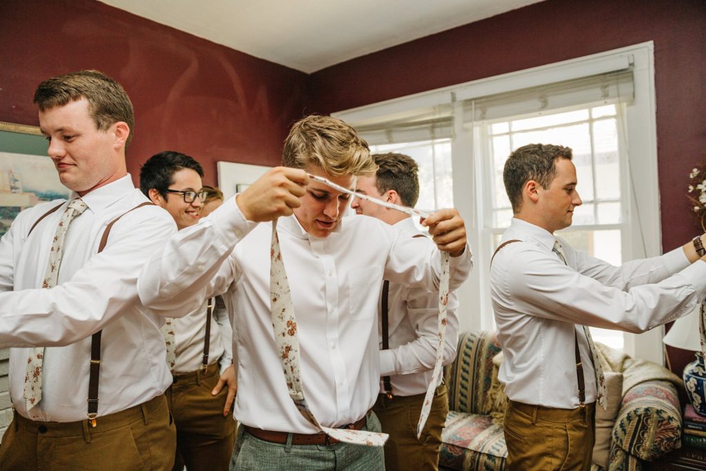 groom putting on floral skinny tie before the wedding