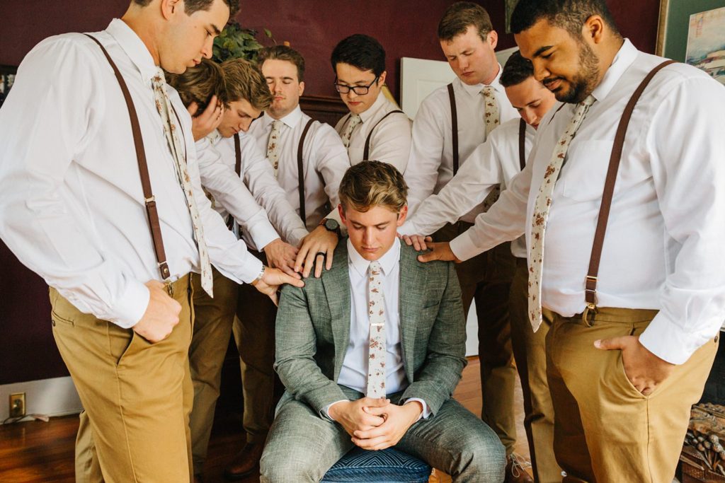 groomsmen praying over the groom before the ceremony