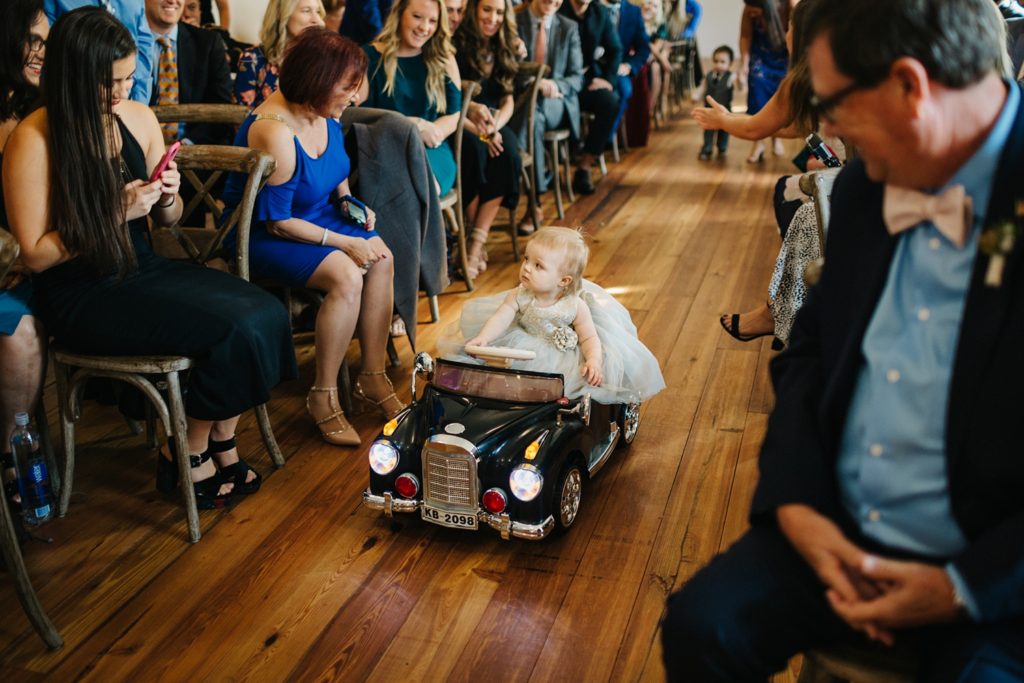 cute flower girl driving vintage toy car down the aisle