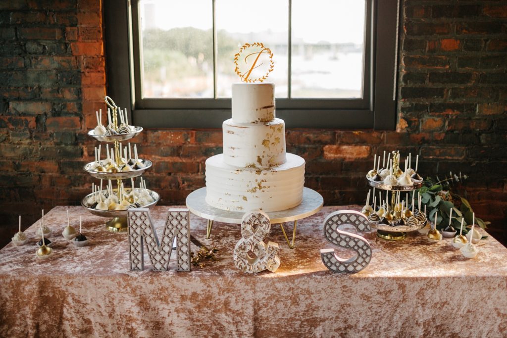 wedding cake with gold leaf accents and cake pops