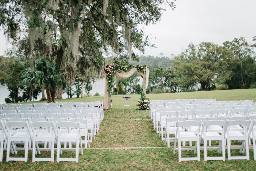 wedding ceremony decor with an arch covered in lush garden blooms and drapery