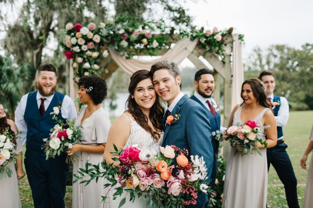 bridal party photos in front of a floral arch