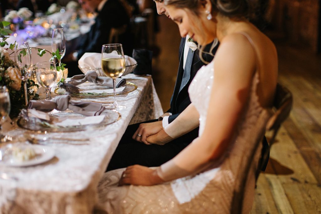 bride and groom holding hands under their sweetheart table
