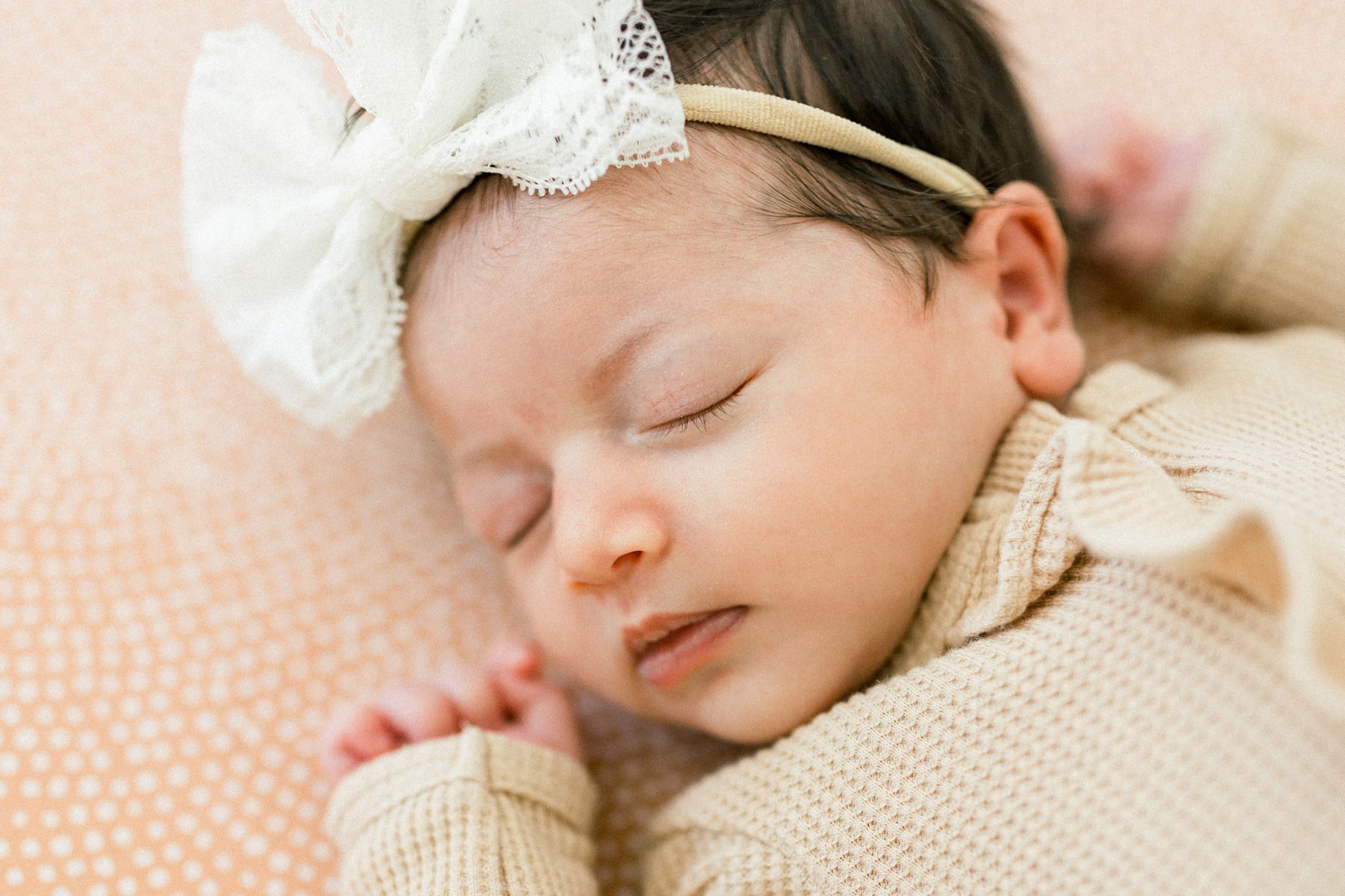 Lifestyle Newborn Photos in the crib with a soft peach neutral crib sheet